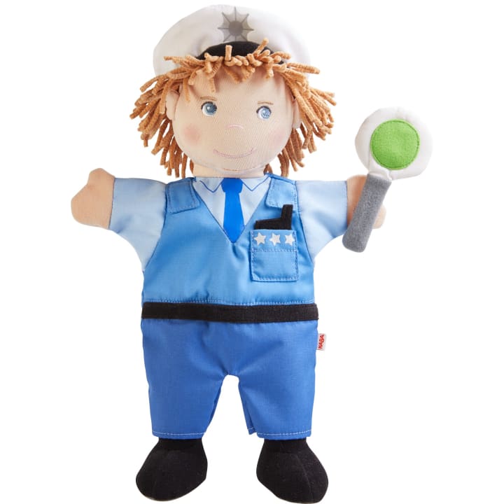 Eine Plüschhandpuppe in Form eines Polizisten mit hellbraunem Garnhaar, weißem Hut, blauer Uniform und einem Spielzeugabzeichen. Die Handpuppe hält in einer Hand ein rundes Schild mit einem grünen Kreis.