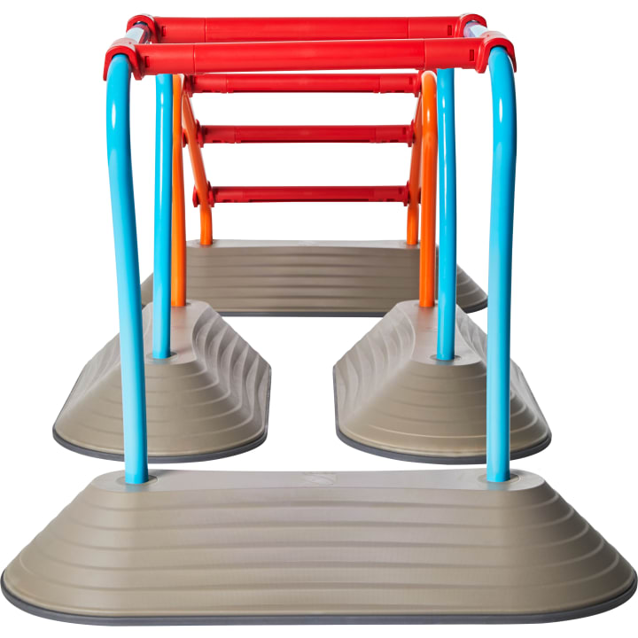 Ein Satz von Spielplatz-Affenstangen mit blauen und orangefarbenen Stützen und roten horizontalen Stangen, montiert auf vier grauen, kuppelförmigen Plattformen.