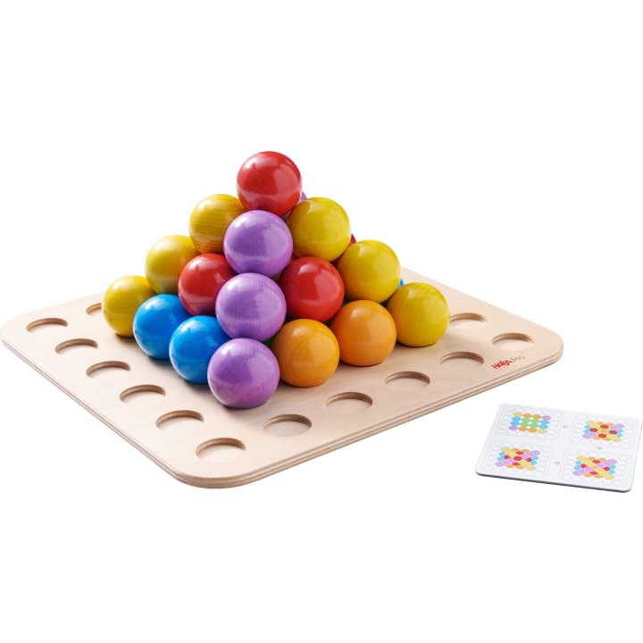 Ein Holzbrett mit Löchern hält eine Pyramide aus großen, bunten Holzkugeln. Neben dem Brett liegt eine kleine Karte, die Muster mit gleichfarbigen Kugeln zeigt.