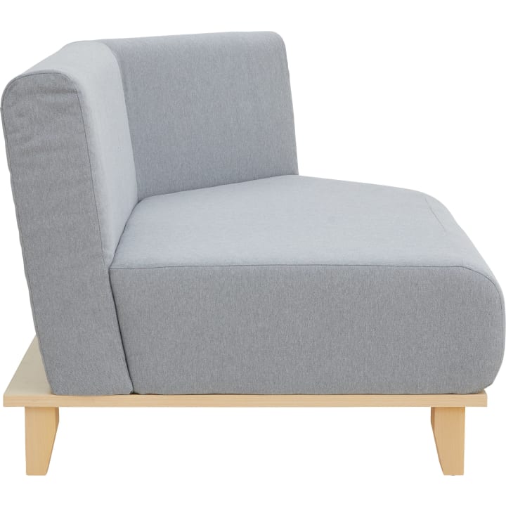Ein hellgrau gepolstertes, armloses Sofa in der Seitenansicht mit dick gepolstertem Sitz und Rückenlehne auf einem hellen Holzgestell mit vier Beinen.
