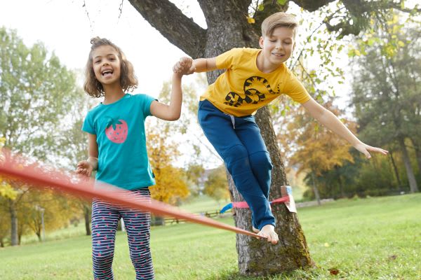 Sport im Park: Kinder spielen mit Slackline