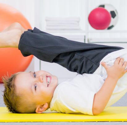 Sportübungen für Kinder: die Krabbe Sportübungen für Kinder: Junge turnt auf Gymnastikmatte