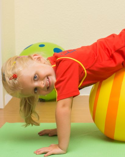 Sportübungen für Kinder: Übungen mit einem Gymnastikball Sportübungen für Kinder: Mädchen turnt mit Gymnastikball