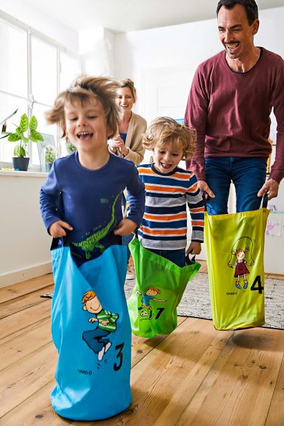 Familienspiel-Ideen: Familie spielt Sackhüpfen Familienspiel-Ideen: Familie spielt Sackhüpfen