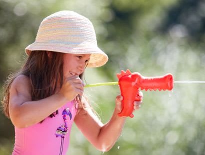 Mädchen spielt Gartenspiel mit Wasserpistole