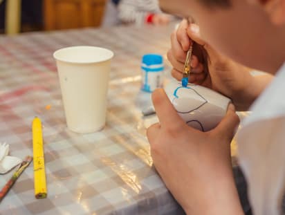 Muttertagsgeschenke basteln: Schlichte Tassen hübsch bemalen Muttertagsgeschenke basteln: Junge malt Herz auf weiße Tasse