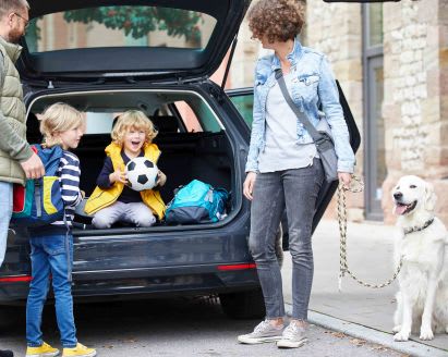 Picknick mit Kindern: Eltern packen Auto mit Proviant und Picknickkorb