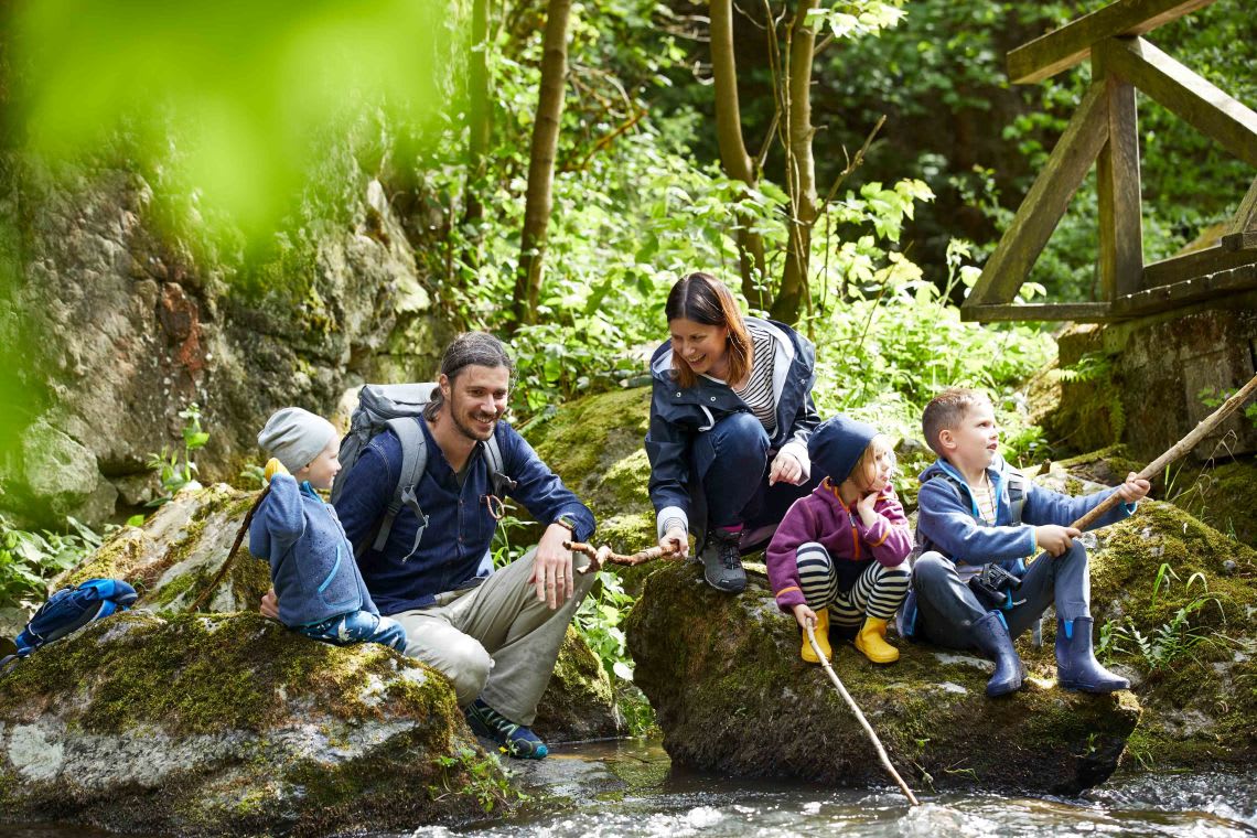 Unternehmungen mit Kindern: unterwegs mit der Familie Unternehmungen mit Kindern: Familie sitzt am Fluss