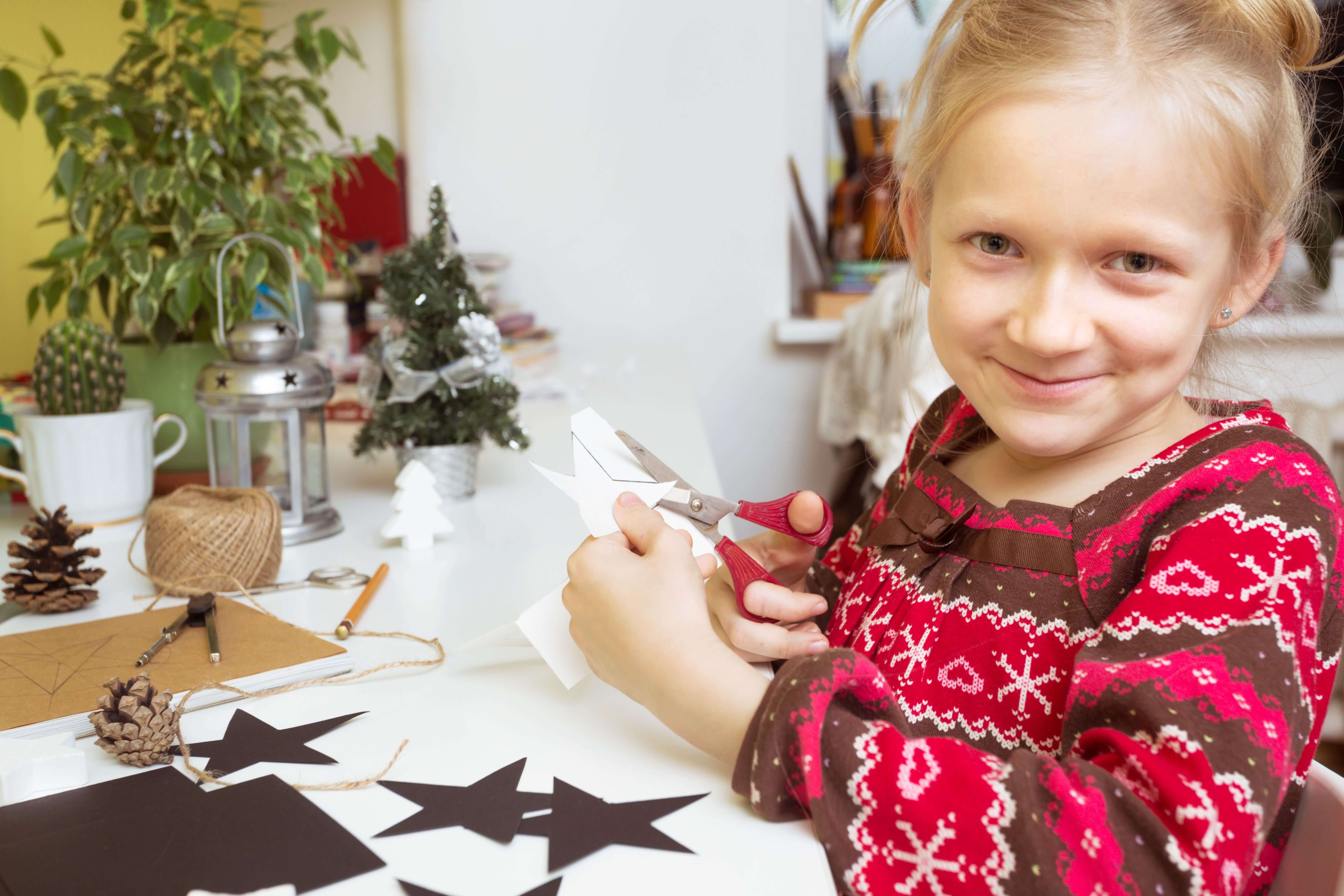 Sterne basteln mit Kindern: Mädchen schneidet Weihnachtssterne aus