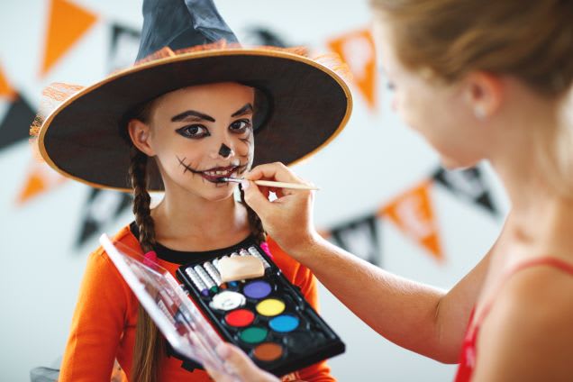 Kinder zu Halloween schminken: Eine Mutter schminkt ihre Tochter mit einer Schminkpalette zur Hexe