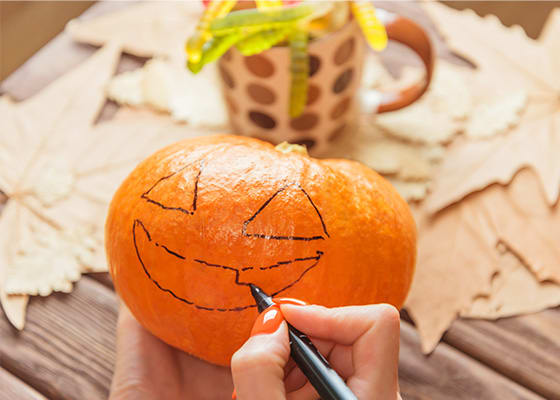 Womans_hands_drawing_a_face_sketch_on_pumpkin_to_Halloween.jpg