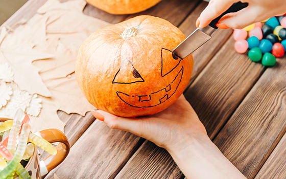 View_of_female_hands_carve_with_knife_a_pumpkin_for_Halloween_holiday.jpg