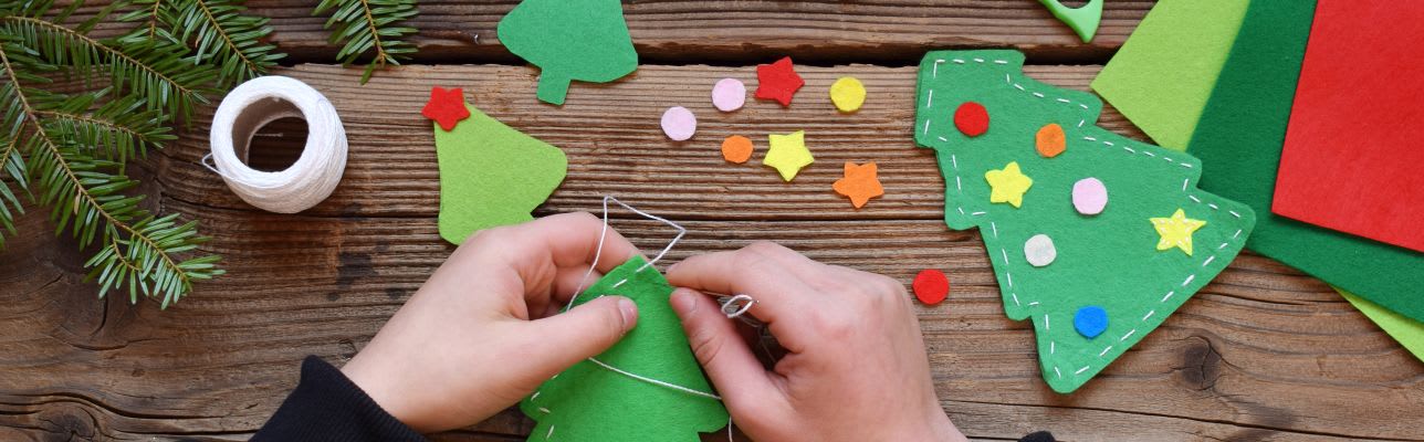 Weihnachtsdeko basteln mit Kindern: Kinderhände basteln Weihnachtsbäume aus Filz