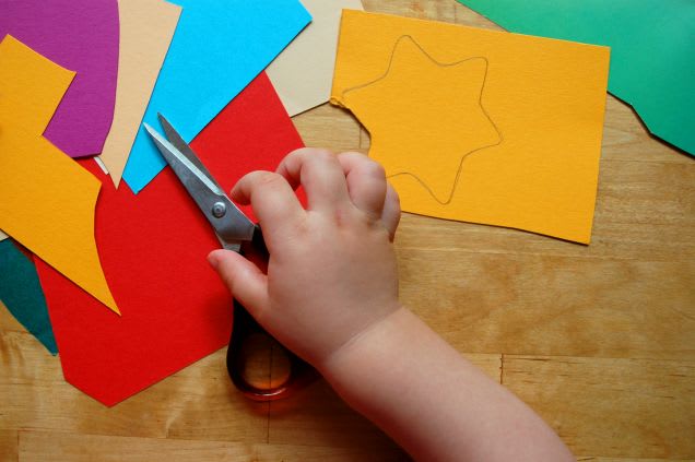 Weihnachtsdeko basteln mit Kindern: Kind schneidet Stern aus Papier aus