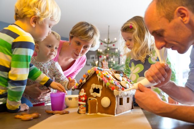 Familie backt mit Kindern ein Lebkuchenhaus für Weihnachten