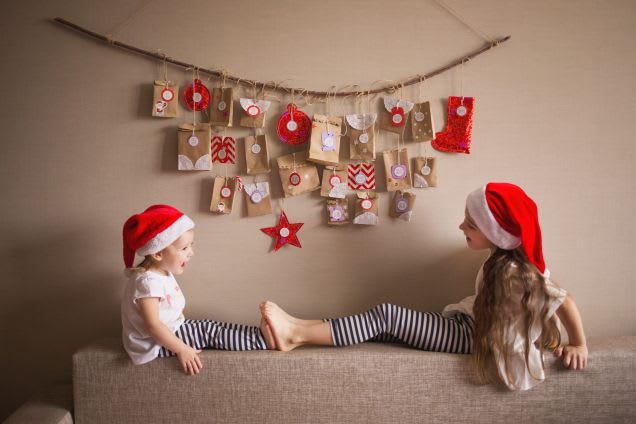 Weihnachten mit Kindern: Geschwister sitzen vor Adventskalender