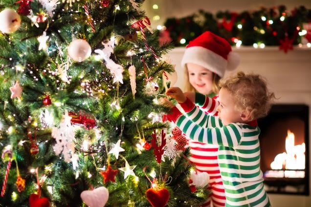 Weihnachten mit Kindern: Geschwister schmücken Tannenbaum