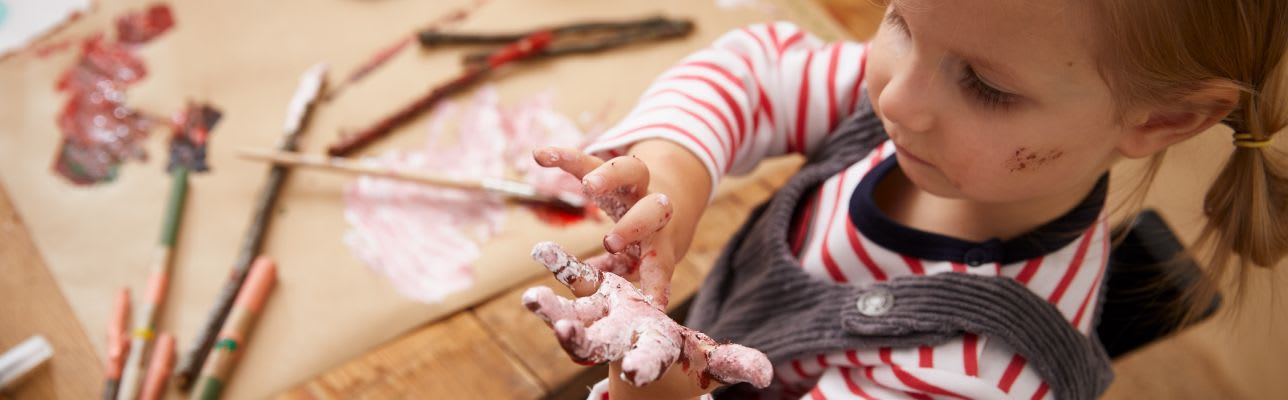 Weihnachtsbaumschmuck basteln mit Kindern: Mädchen mit Farbe an den Händen