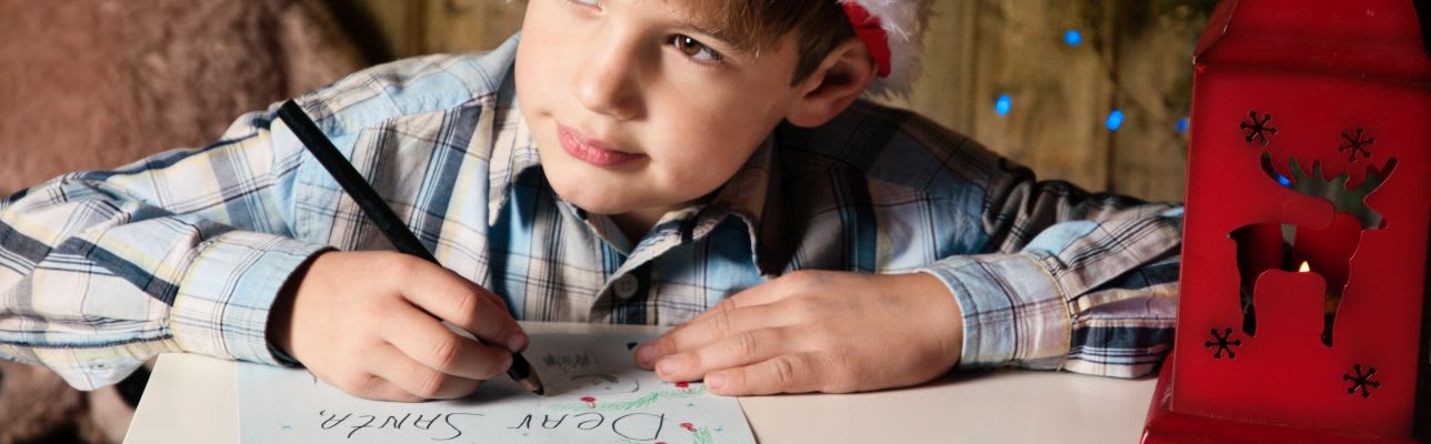 Junge schreibt Wunschzettel für Weihnachten