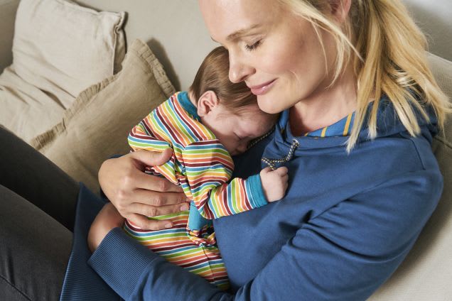 Erstausstattung Babys im Herbst: Mutter kuschelt mit Baby