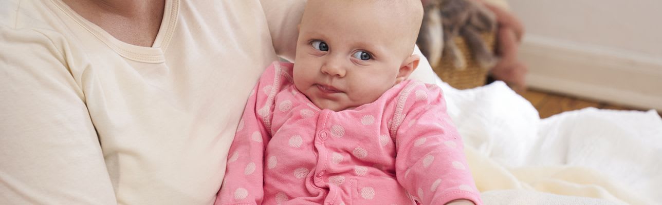 Erstausstattung Babys im Frühling: Kind mit rosa Strampler