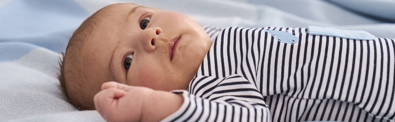 Erstausstattung Babys im Frühling: Kind liegt im Bettchen