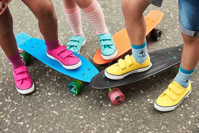 Schuhgröße messen bei Kindern: Kinder mit bunten Schuhen auf Skateboards
