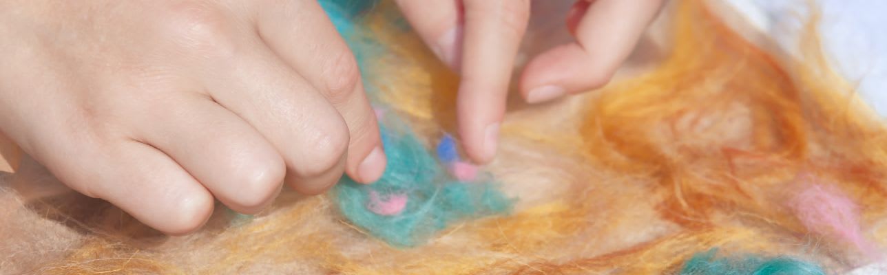 Filzen mit Kindern: Kinderhände drücken Filzwolle aufeinander