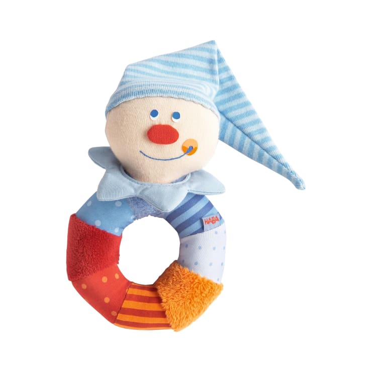 Eine weiche Plüsch-Babyrassel in Form eines Clowns mit rundem Griff, bunten Teilen, einem blau gestreiften Hut, einem lächelnden Gesicht und einer roten Nase.