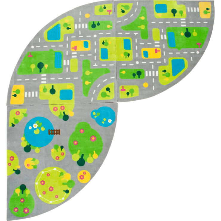 Eine graue Spielmatte mit einem farbenfrohen Stadtplan, der Straßen, Kreuzungen, grüne Parks, blaue Teiche, gelbe Gebäude und kleine Bäume in einer ovalen, blattähnlichen Form zeigt.