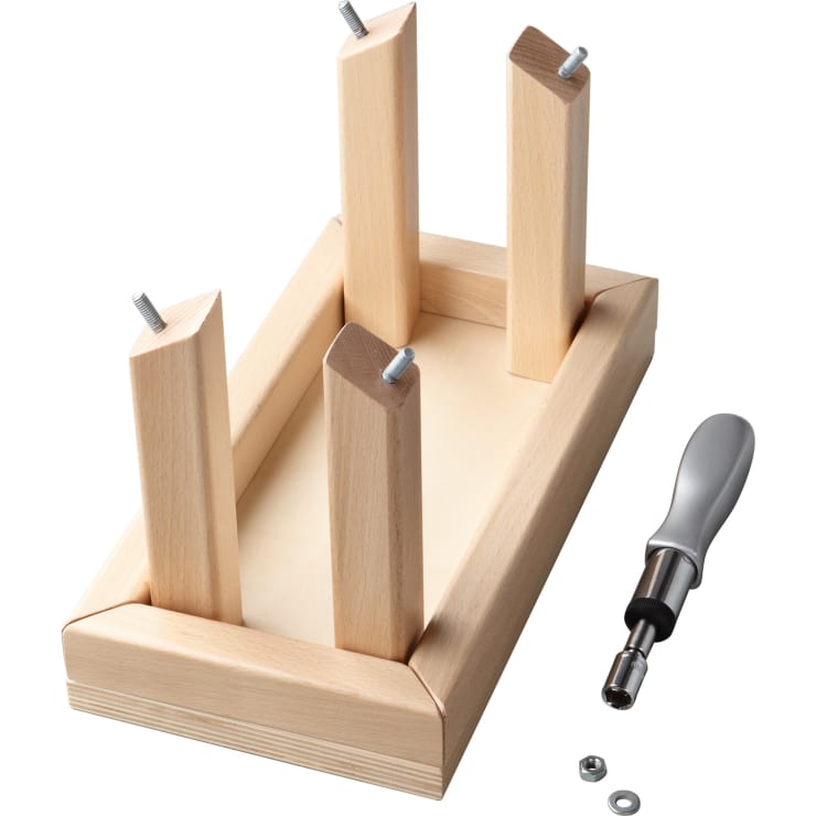 Ein kleiner rechteckiger Holztisch, der auf den Kopf gestellt ist und dessen vier Beine mit Schrauben, einem Schraubenzieher, einer Unterlegscheibe und einer Mutter befestigt sind, steht in der Nähe auf einem weißen Hintergrund.