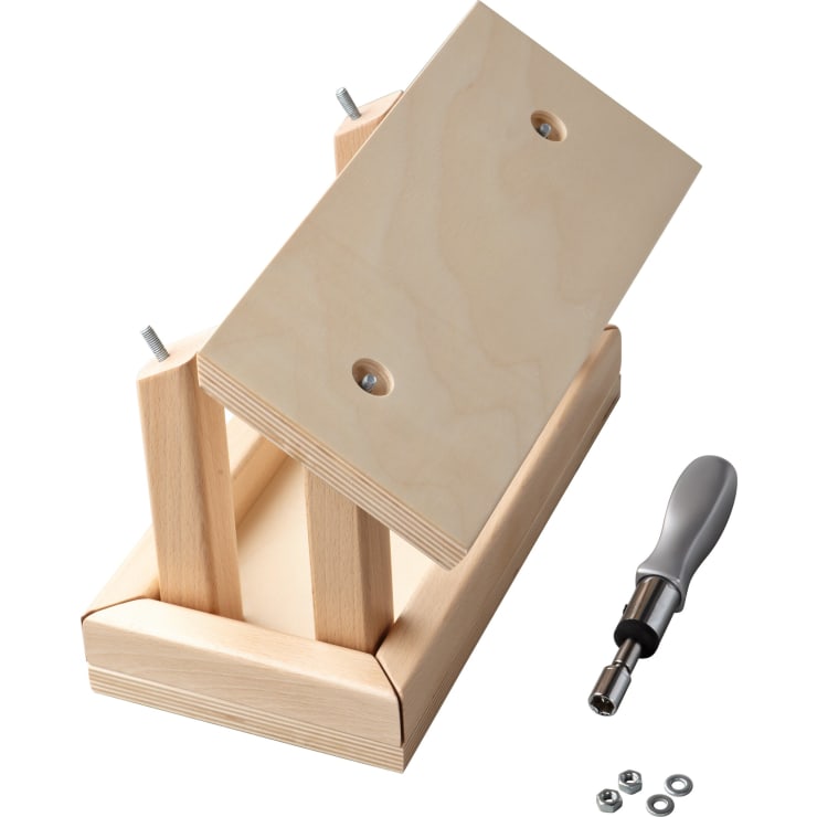 Eine kleine Holzbank wird zusammengebaut, wobei ein Schraubenzieher, Schrauben und Unterlegscheiben in der Nähe liegen. Die Bank besteht aus hellen Holzbrettern und zwei teilweise eingesteckten Bolzen.