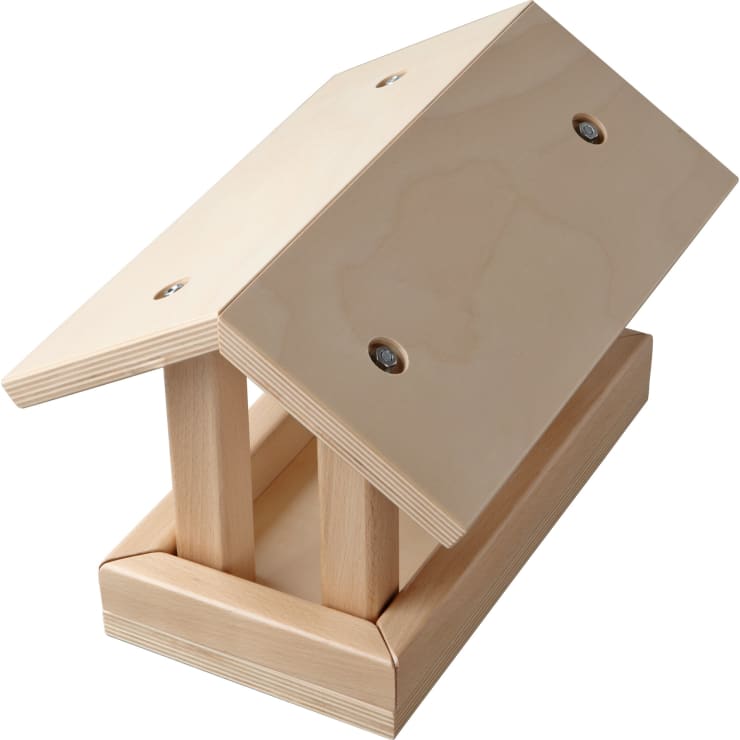 Ein einfaches Vogelfutterhaus aus Holz mit schrägem Dach und offenen Seiten, hergestellt aus hellem Holz und mit sichtbaren Schrauben zusammengebaut. Das Futterhaus ist leer und wurde vor einem weißen Hintergrund fotografiert.