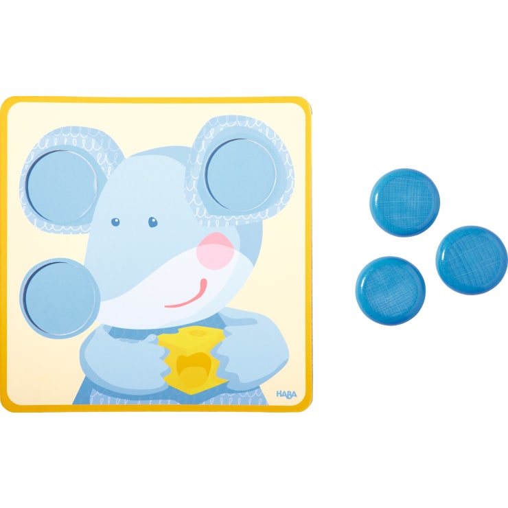 Ein quadratisches Puzzlebrett zeigt eine Cartoon-Maus, die einen Käse in der Hand hält und aus deren Kopfbereich drei runde Teile entfernt wurden. Drei blaue kreisförmige Teile liegen rechts vom Brett, bereit, in das Puzzle eingepasst zu werden.