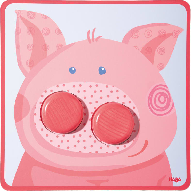 Eine einfache Illustration eines rosafarbenen Schweinegesichts mit zwei abnehmbaren runden roten Stücken an der Stelle, an der sich die Nasenlöcher befinden würden. Der Hintergrund und die Ränder sind ebenfalls rosa. Das HABA-Logo erscheint in der unteren rechten Ecke.