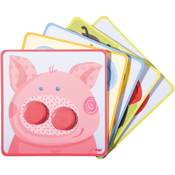 Ein Stapel illustrierter Tierpuzzleplatten, wobei die oberste Platte ein rosafarbenes Schweinegesicht und zwei rote runde Teile anstelle der Nasenlöcher zeigt. Andere Tiertafeln sind teilweise darunter sichtbar.
