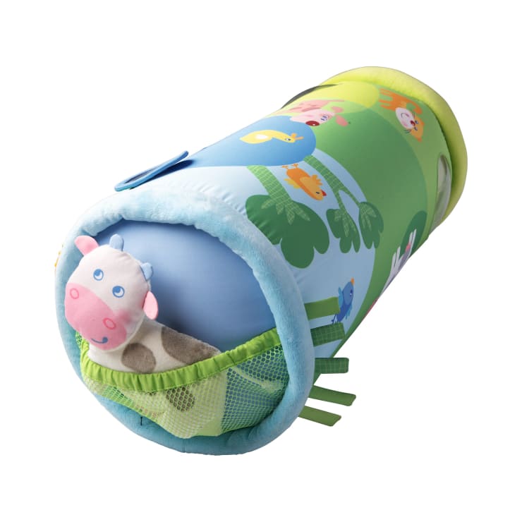 Ein zylindrisches, farbenfrohes Stofftier mit Tierillustrationen und einem Plüschkuhkopf, der aus einer Netztasche an einem Ende herausragt. Das Spielzeug hat blaue, grüne und gelbe Abschnitte mit Schleifenanhängern an der Seite.