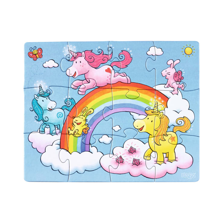 Ein farbenfrohes Puzzle mit Einhörnern und Hasen auf Wolken um einen Regenbogen unter einem blauen Himmel mit einer Sonne und einem Schmetterling. Die Einhörner sind rosa, blau und gelb und haben einen verspielten Gesichtsausdruck.