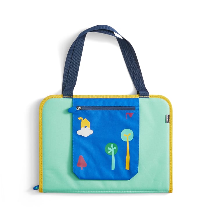 Eine rechteckige Tragetasche mit schwarzen Griffen, einem hellgrünen Korpus, gelben Verzierungen und einer blauen Vordertasche, die mit einfachen Baum- und Hausgrafiken verziert ist. Die Tasche hat einen Reißverschluss an der Oberseite.