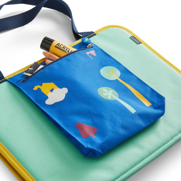 Eine blaue Reißverschlusstasche mit bunten Baum- und Wolkengrafiken fasst Marker und Stifte und ist an einer gepolsterten mintgrünen Tasche mit gelben Rändern und einem marineblauen Riemen befestigt.