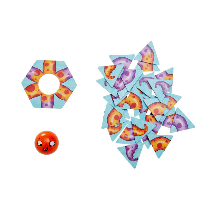 Ein Sortiment von dreieckigen Spielsteinen mit Tentakelmotiven, ein sechseckiger Ring mit orangefarbenen und gelben Mustern und ein orangefarbener Spielstein mit einem Cartoon-Gesicht, alles auf weißem Hintergrund.