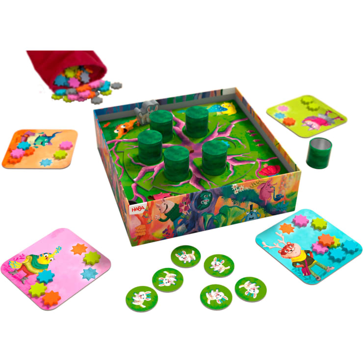 Ein farbenfrohes Brettspiel mit einer Schachtel mit Baummotiv, grünen runden Spielsteinen, vier illustrierten Spielertafeln mit Tierfiguren, sternförmigen Spielsteinen und runden, verstreuten Tiersteinen.