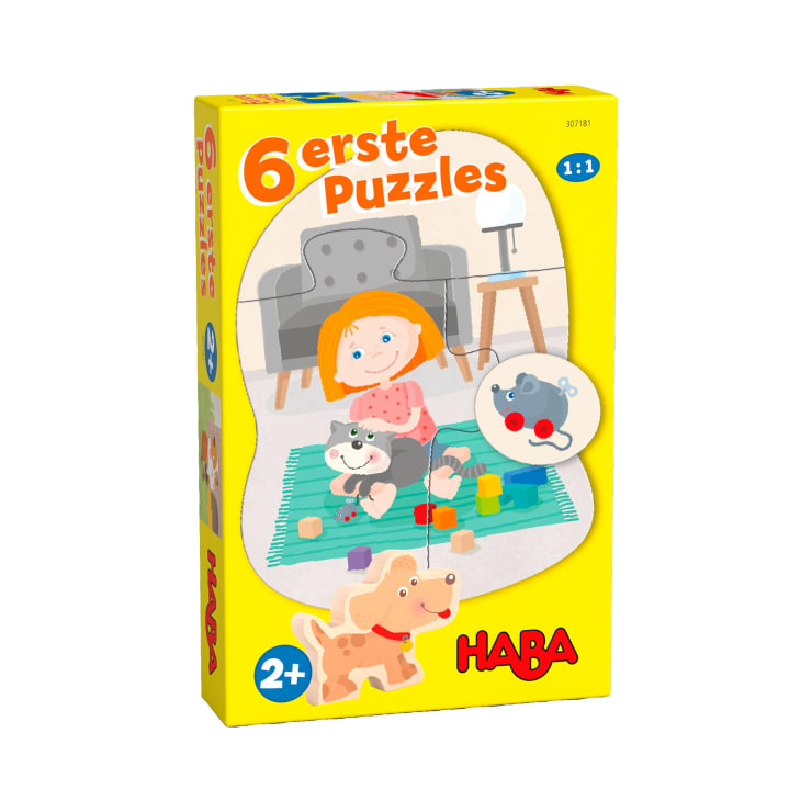 Eine gelbe Schachtel mit den "6 ersten Puzzles" von HABA für Kinder ab 2 Jahren. Auf der Schachtel ist ein Kind abgebildet, das in einem Wohnzimmer mit einem Hund und Bauklötzen spielt. Auf der Schachtel sind ein Cartoon-Hund und eine Maus abgebildet.