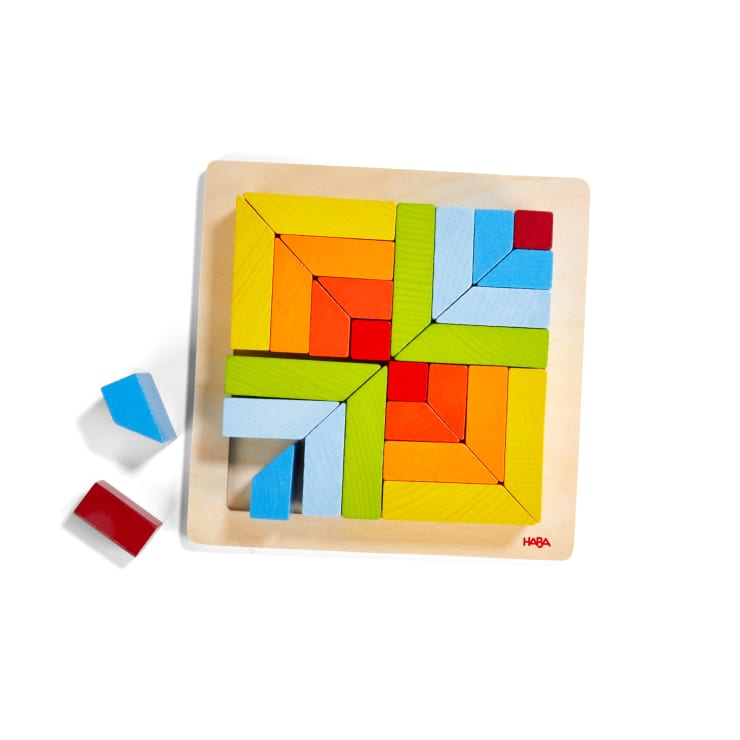 Ein Holzpuzzle mit bunten geometrischen Blöcken, die in einem quadratischen Muster auf einem Holzsockel angeordnet sind. Einige blaue und rote Blöcke befinden sich außerhalb des Puzzles auf der linken Seite. Das HABA-Logo ist in der unteren rechten Ecke zu sehen.