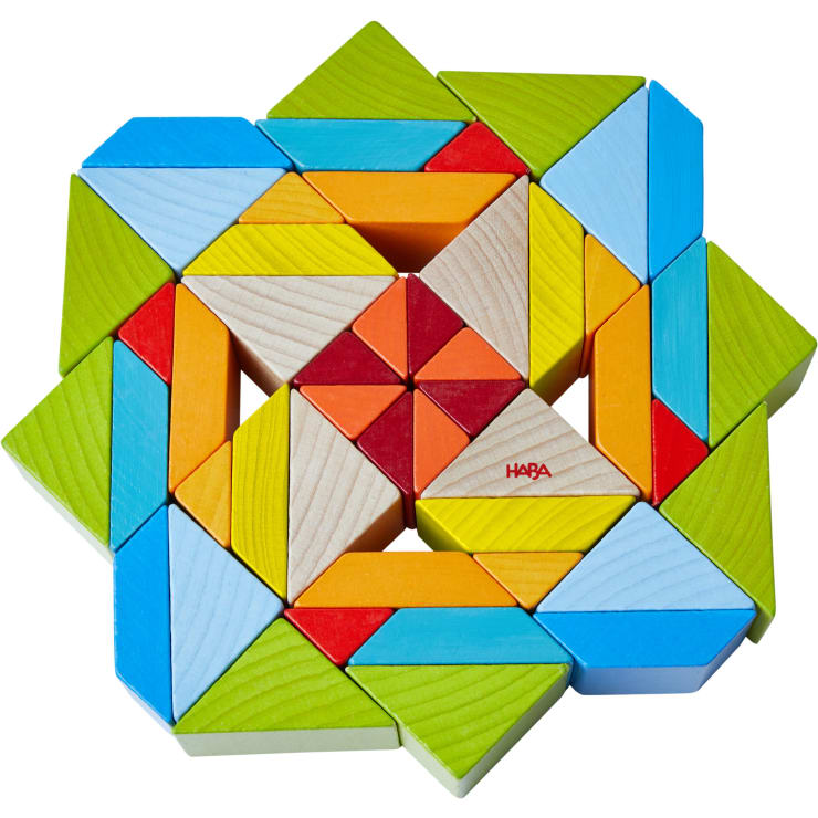 Ein geometrisches Muster aus bunten Holzklötzen, darunter Dreiecke und Rechtecke in Blau, Grün, Gelb, Orange, Rot und Naturholz. Die Teile sind in einem symmetrischen, sternförmigen Muster angeordnet.