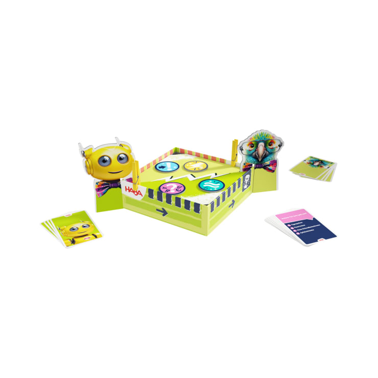 Ein Tischspiel mit einer gelben Spielschachtel, Spielfiguren, Kartendecks und einem sich drehenden Rad mit Tiergesichtern. Das Spiel ist farbenfroh gestaltet und steht vor einem weißen Hintergrund.
