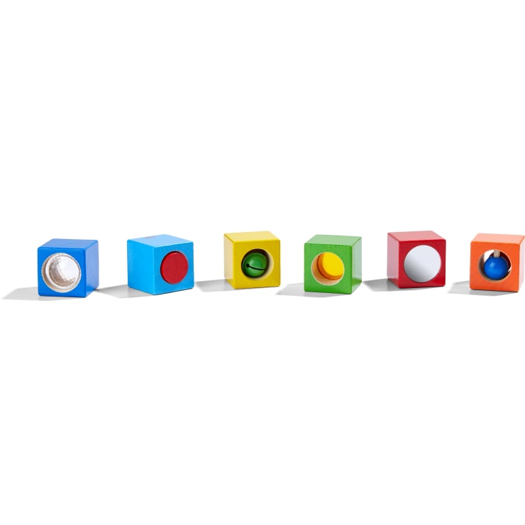 Sechs bunte Holzklötze sind in einer Reihe aufgereiht, jeder mit einer anderen Farbe und einem einzigartigen Objekt oder Merkmal in einer kreisförmigen Öffnung auf einer Seite.