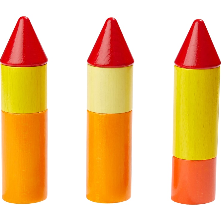 Drei bunte Holzspielzeugraketen stehen aufrecht in einer Reihe, jede mit einem gelben und orangen Körper und einer roten Spitze. Die Spielzeuge scheinen aus glatt lackiertem Holz gefertigt zu sein.