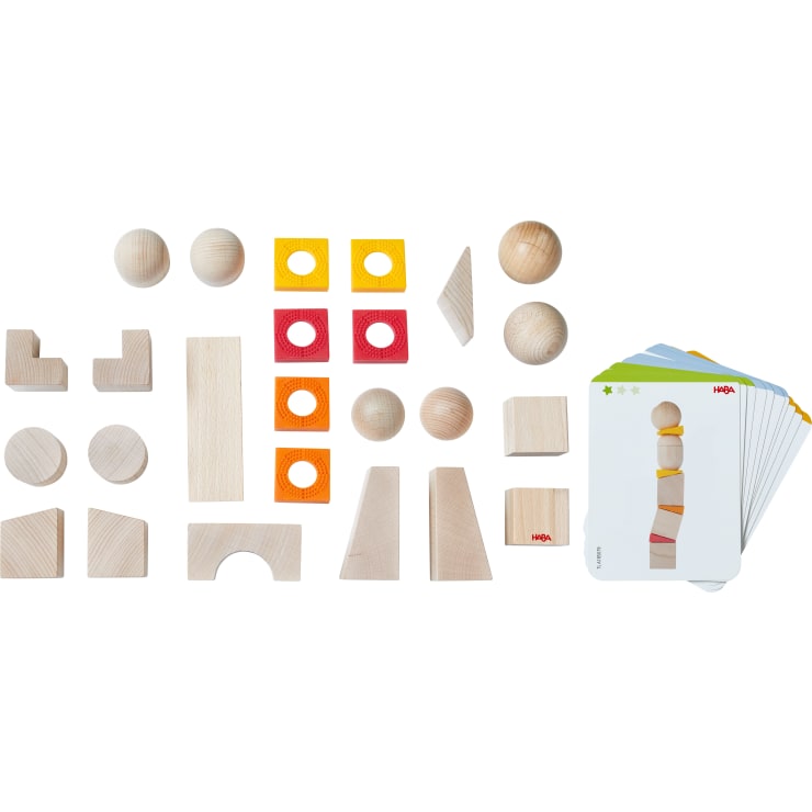Ein Satz verschiedener Holzbauklötze, bunte quadratische Teile mit Löchern und mehrere Karten mit Bildern von Klötzchenanordnungen, die alle auf einer weißen Fläche ausgelegt sind.