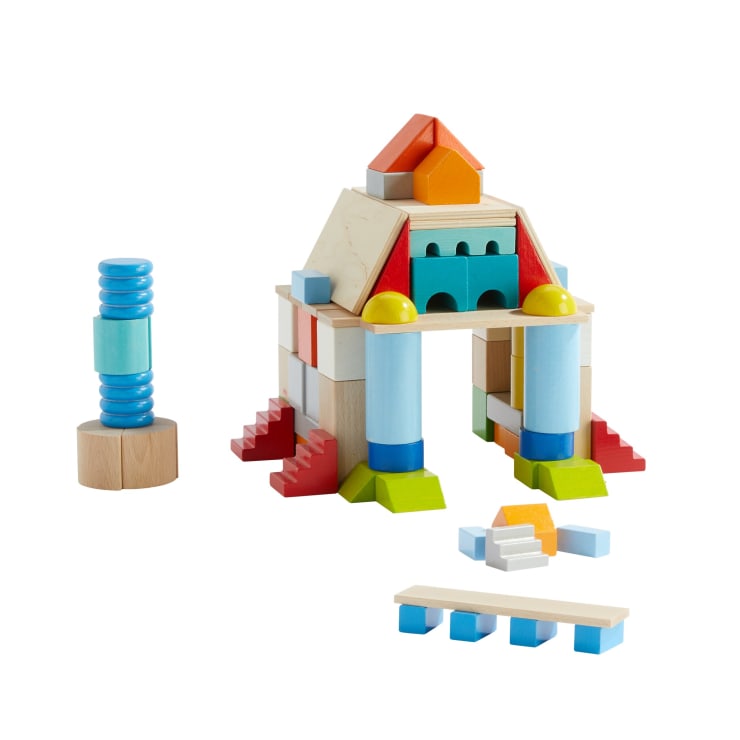 Ein Satz bunter Holzbausteine, die so angeordnet sind, dass sie ein kleines Bauwerk mit Säulen, Treppen und Bögen bilden, daneben ein blaues Stapelspielzeug und mehrere lose Blöcke auf weißem Hintergrund.